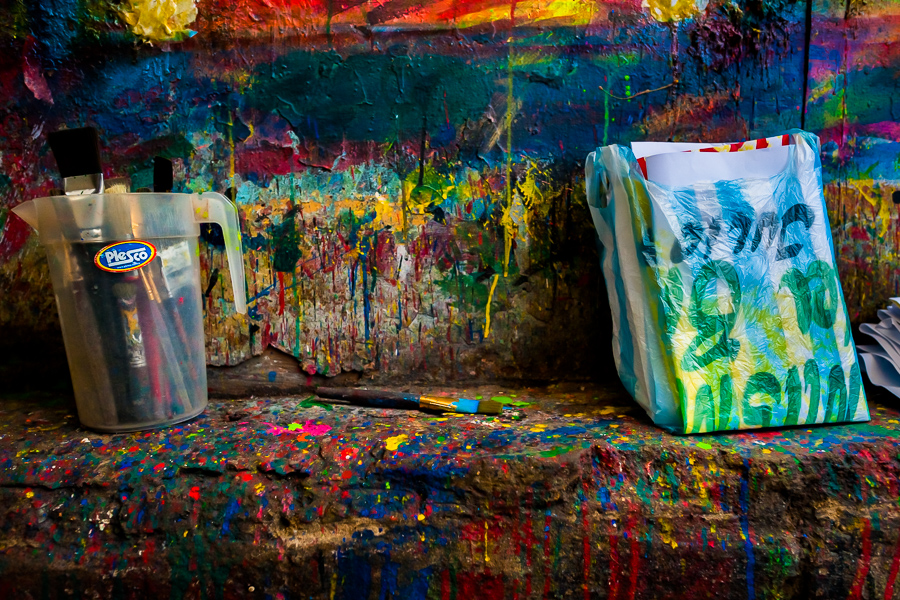 Clean brushes and folded posters, available to pick up, are seen placed on a splattered kerb in the sign painting workshop in Cartagena, Colombia.