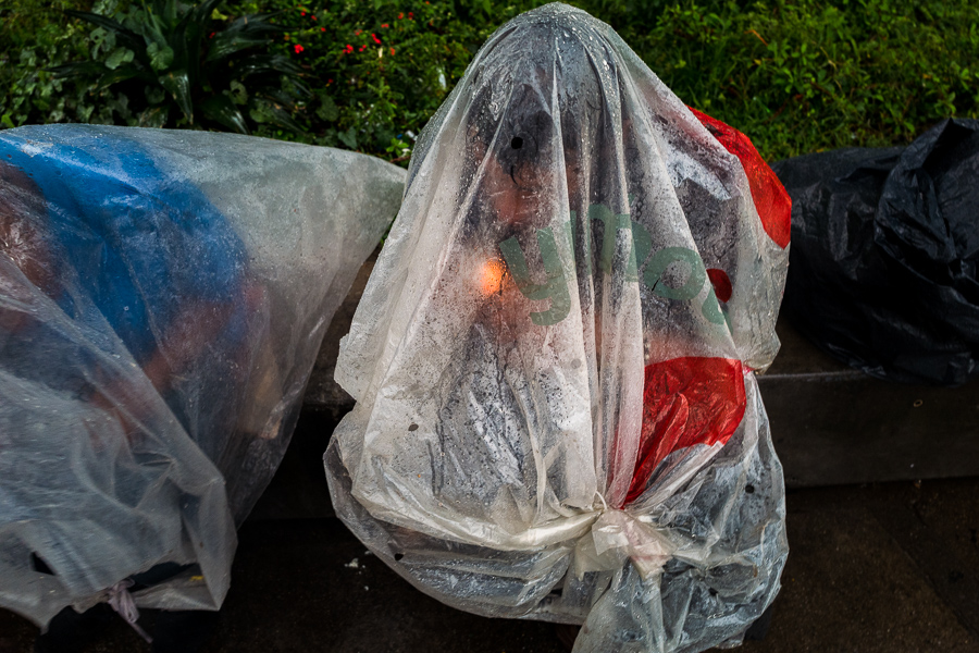 Colombian men smoke “bazuco” (a raw cocaine paste), hidden inside a large plastic bag in the streets of “El Bronx”, a drug distribution area in Medellín, Colombia.