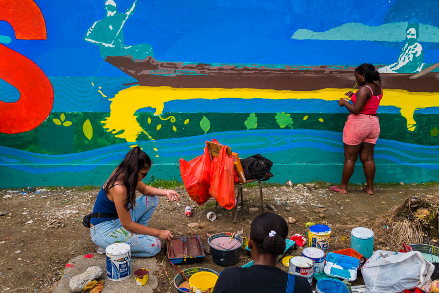 Afro-Colombian female students paint a society and environment-related mural on a school wall in Quibdó, Colombia.