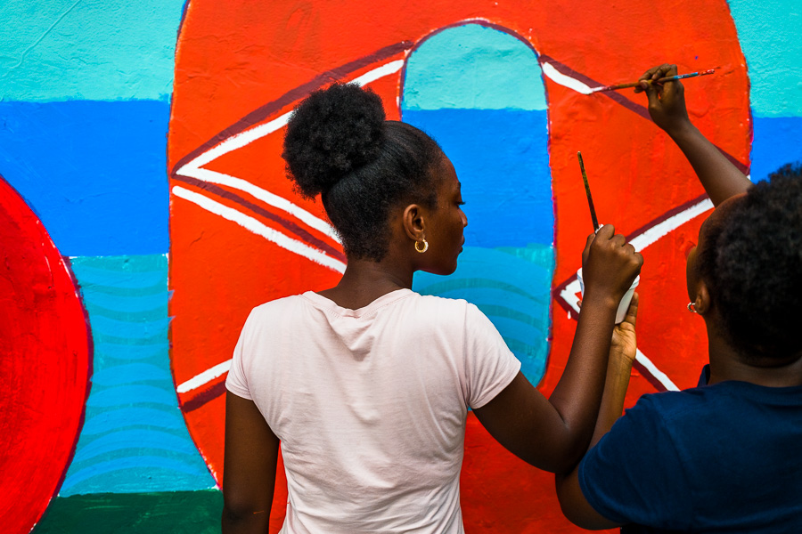 Afro-Colombian female students paint a society and environment-related mural on a school wall in Quibdó, Colombia.