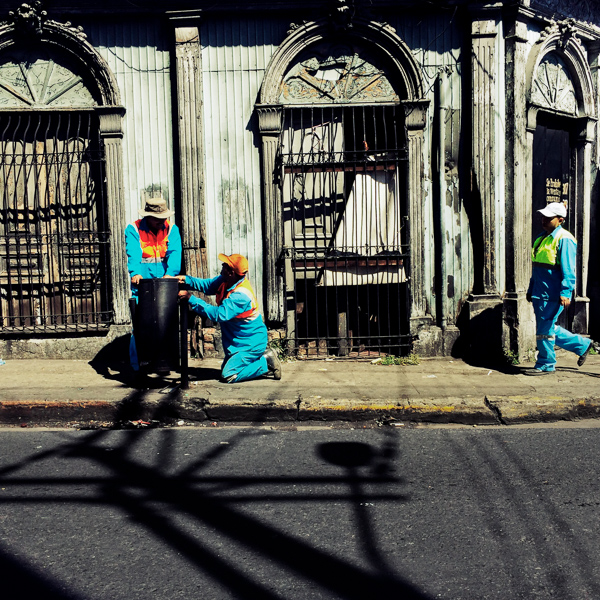 Salvadoran garbage collectors work in front of a ruined house, designed by using bold Spanish colonial architecture elements, built in the center of San Salvador, El Salvador.