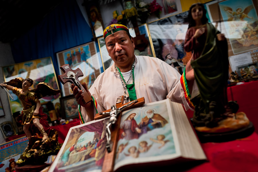 Hermes Cifuentes, a Colombian spiritual healer, prays at an altar in his apartment before performing a ritual of exorcism in La Cumbre, Colombia.