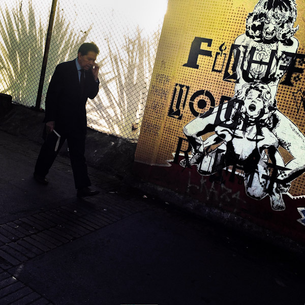 A Colombian businessman walks in front of a stencil artwork, reading “Fight for your right”, in the center of Bogotá, Colombia.