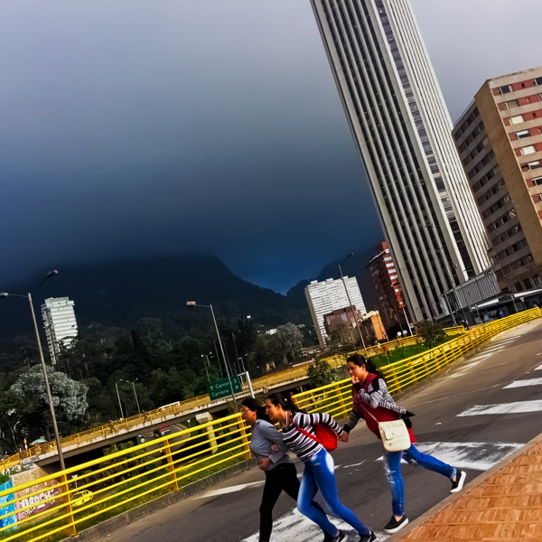 Colombian girls rush to shelter from the coming storm when they walk across the street in Bogotá, Colombia.