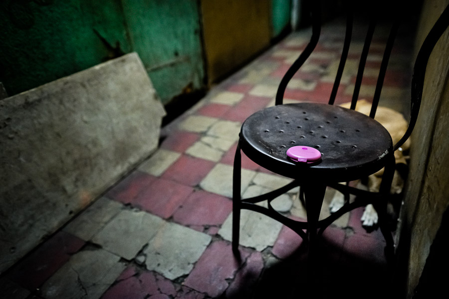 A pink powder box, belonging to a sex worker, lies on a chair in front of a room where sexual services are offered to clients in San Salvador, El Salvador.