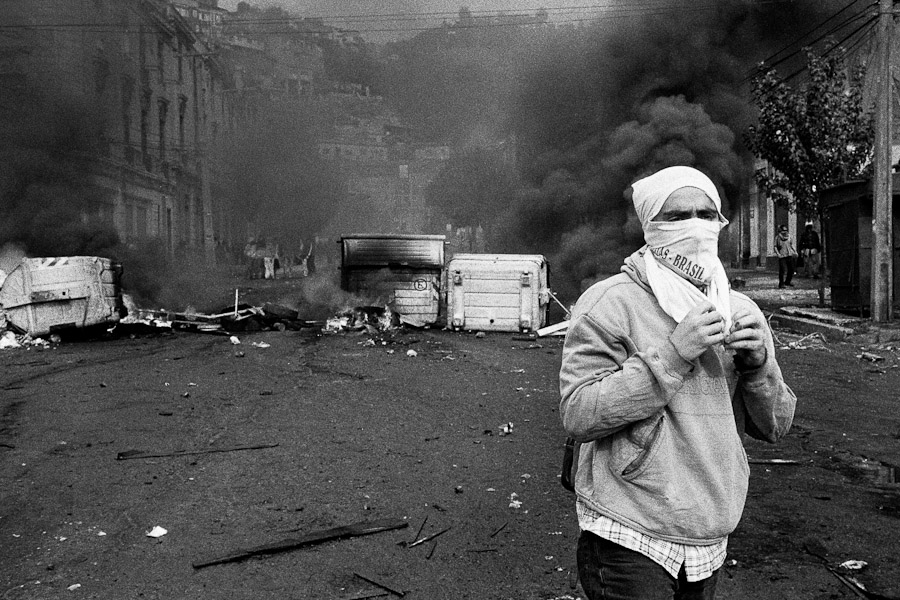 A Chilean student stands in front of the burning barricade during the anti-government protest in Valparaíso, Chile.