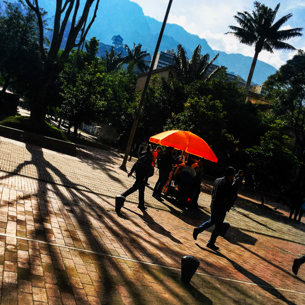 Colombian students pass along a street food cart during the sunrise in La Candelaria, Bogotá, Colombia.