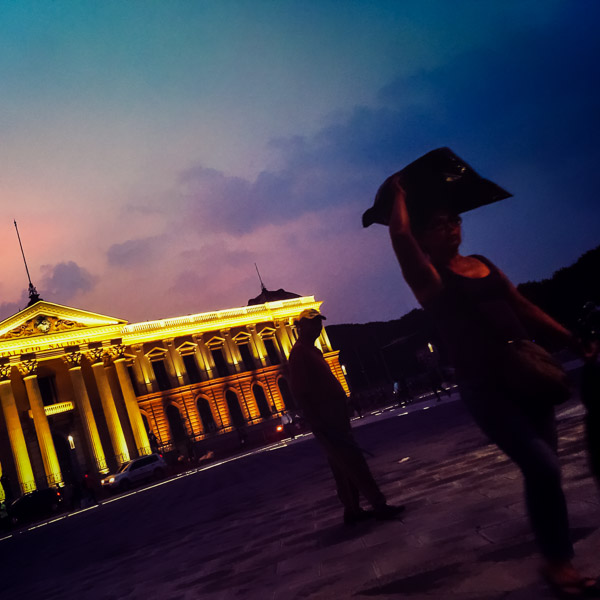 A Salvadoran street vendor, carrying a plastic bag on her head, walks in front of Palacio Nacional at Plaza Gerardo Barrios, San Salvador, El Salvador.