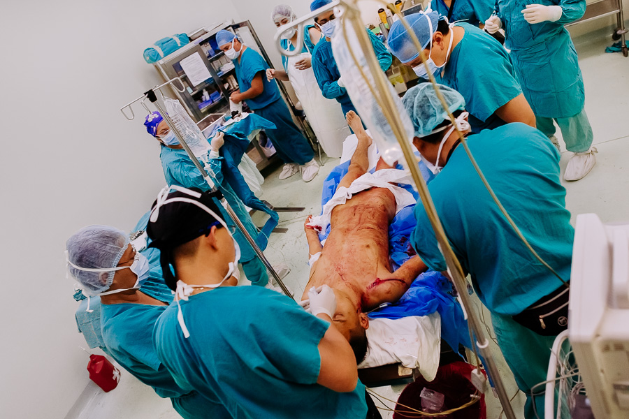 A team of physicians prepare a young gang member, with three gunshot wounds, for a surgery in the operating room of a public hospital in San Salvador, El Salvador.