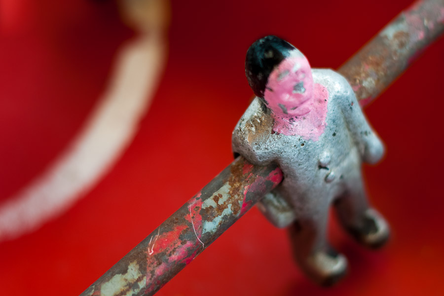 Table football player mounted on rusted bar.