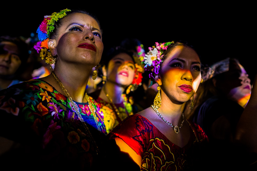 Mexican women, wearing traditional Tehuana dress, watch the stage during a local dance fiesta in Oaxaca, Mexico.