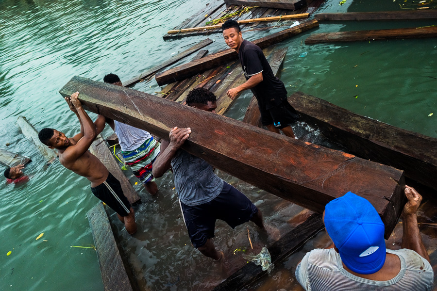 Afro-Colombian workers carry a rough sawn timber during wood transportation in the port of Turbo, Colombia.