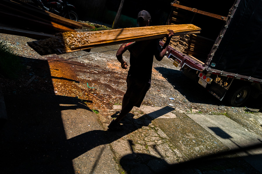 An Afro-Colombian carrier loads rough sawn boards onto a truck during wood transportation in the port of Quibdó, Colombia.
