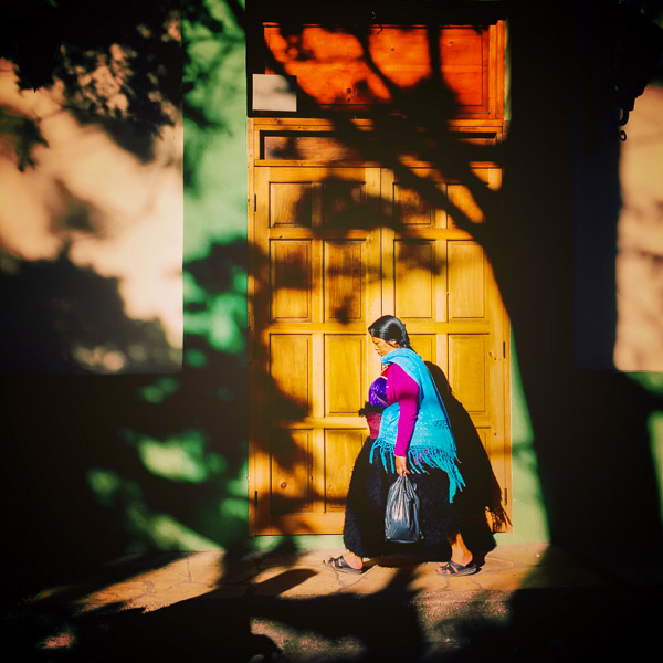 An indigenous Tzotzil Maya woman, wearing a traditional black wool skirt, walks on the street of San Cristóbal de las Casas, Chiapas, Mexico.