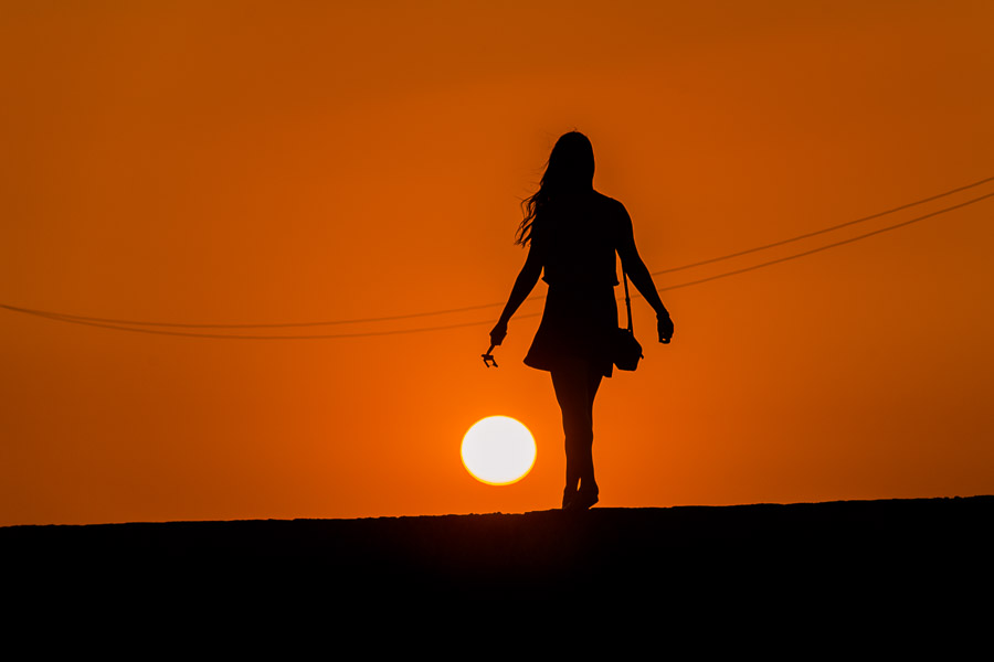 A young female tourist walks on the stone walls, surrounding the colonial walled city, during the sunset in Cartagena, Colombia.