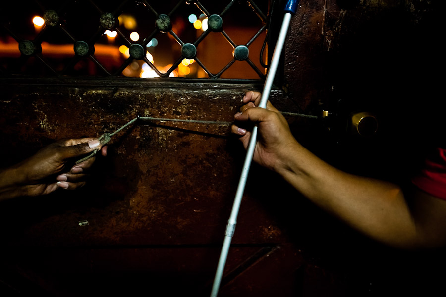 A blind man, holding a white cane, opens the door of Unión Nacional de Ciegos del Perú, a social club for the visually impaired in Lima, Peru.