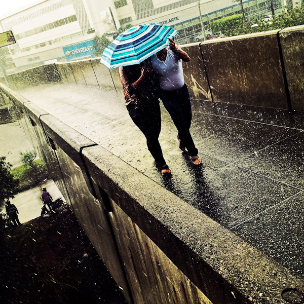 Colombian women walk under umbrella during a heavy afternoon rainstorm in Itagüí, Medellín, Colombia.