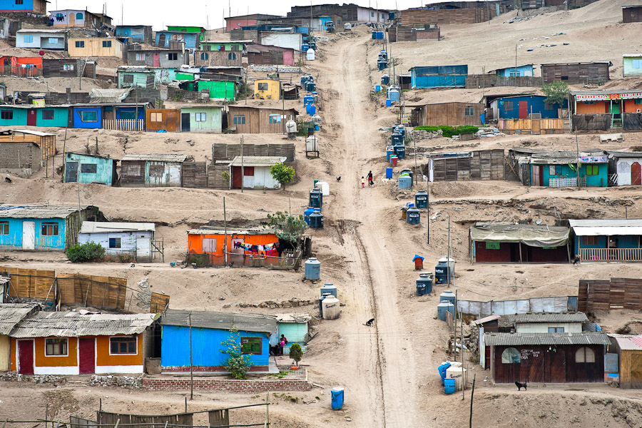 A Peruvian woman with her child climb up a steep path along the plastic water containers and tanks on the dusty hillside of Pachacútec, a desert suburb of Lima, Peru.