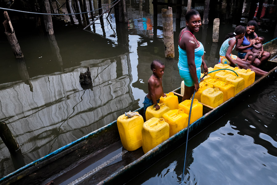 A Colombian woman fills plastic barrels with safe drinking water inside the stilt house area in Tumaco, Colombia.