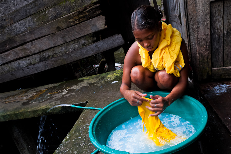 A Colombian girl washes clothes in a bucket, outside a wooden house in the stilt house area in Tumaco, Colombia.