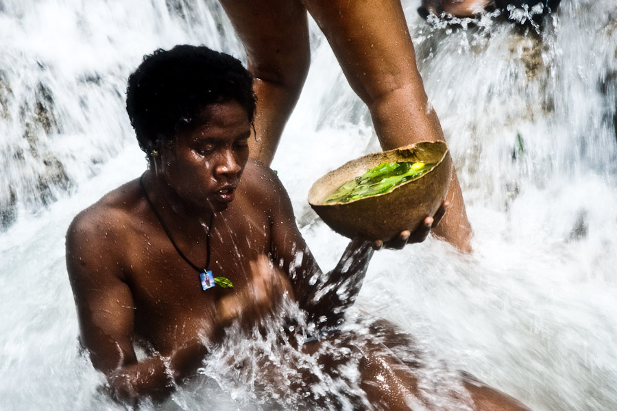 A Haitian woman performs a bathing and cleaning ritual, using medicinal herbs, under the waterfall during the annual religious pilgrimage in Saut d'Eau, Haiti.