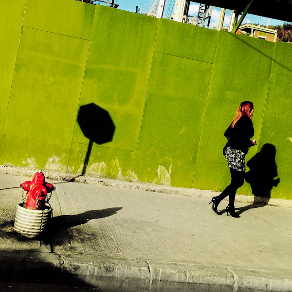 A Colombian woman walks down the sidewalk, passing by a hydrant in front of the construction site in the center of Bogotá, Colombia.