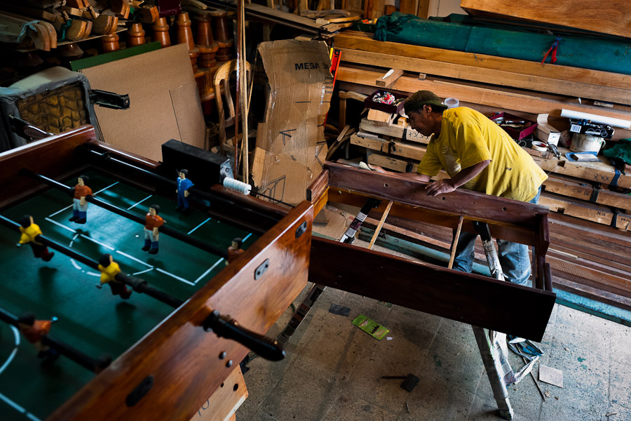 Fabian R., a carpentry worker, polishes the wooden case with a fine sandpaper at a table football workshop in Quito, Ecuador.