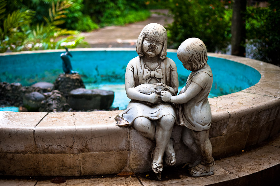 An empty fountain with a broken statue of girls holding a rabbit at the Havana Zoo.